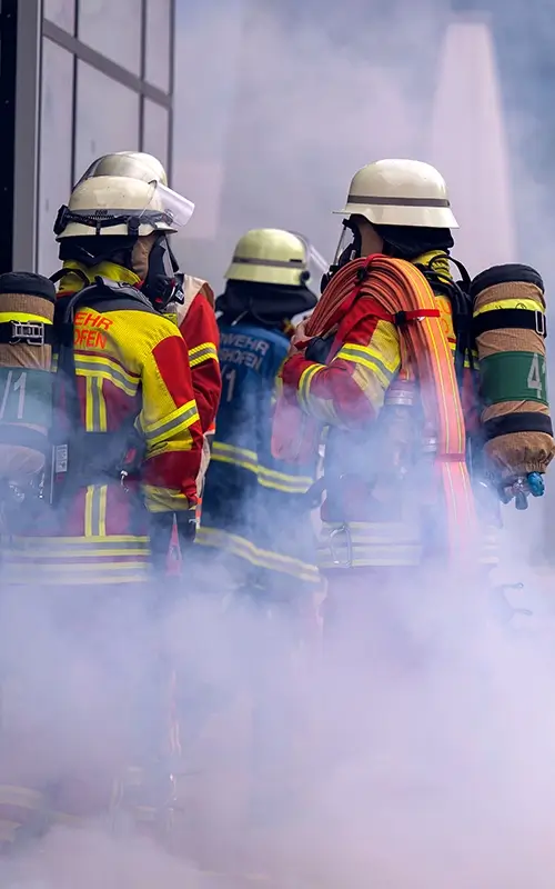 Feuerwehrmänner stehen im Rauch und besprechen sich